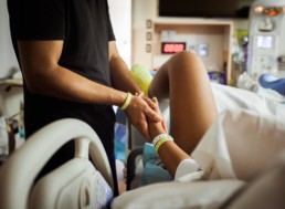 Father holds hand of laboring woman in childbirth during a contraction, photo of dad supporting mom during labor in hospital room by holding hands