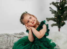 Toddler in green dress poses for holiday photograph