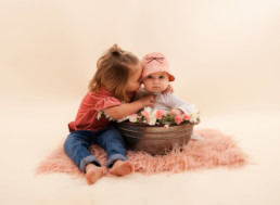 Sisters sit for in studio photo shoot in Pasadena, California with a bucket of flowers for Valentine's day session