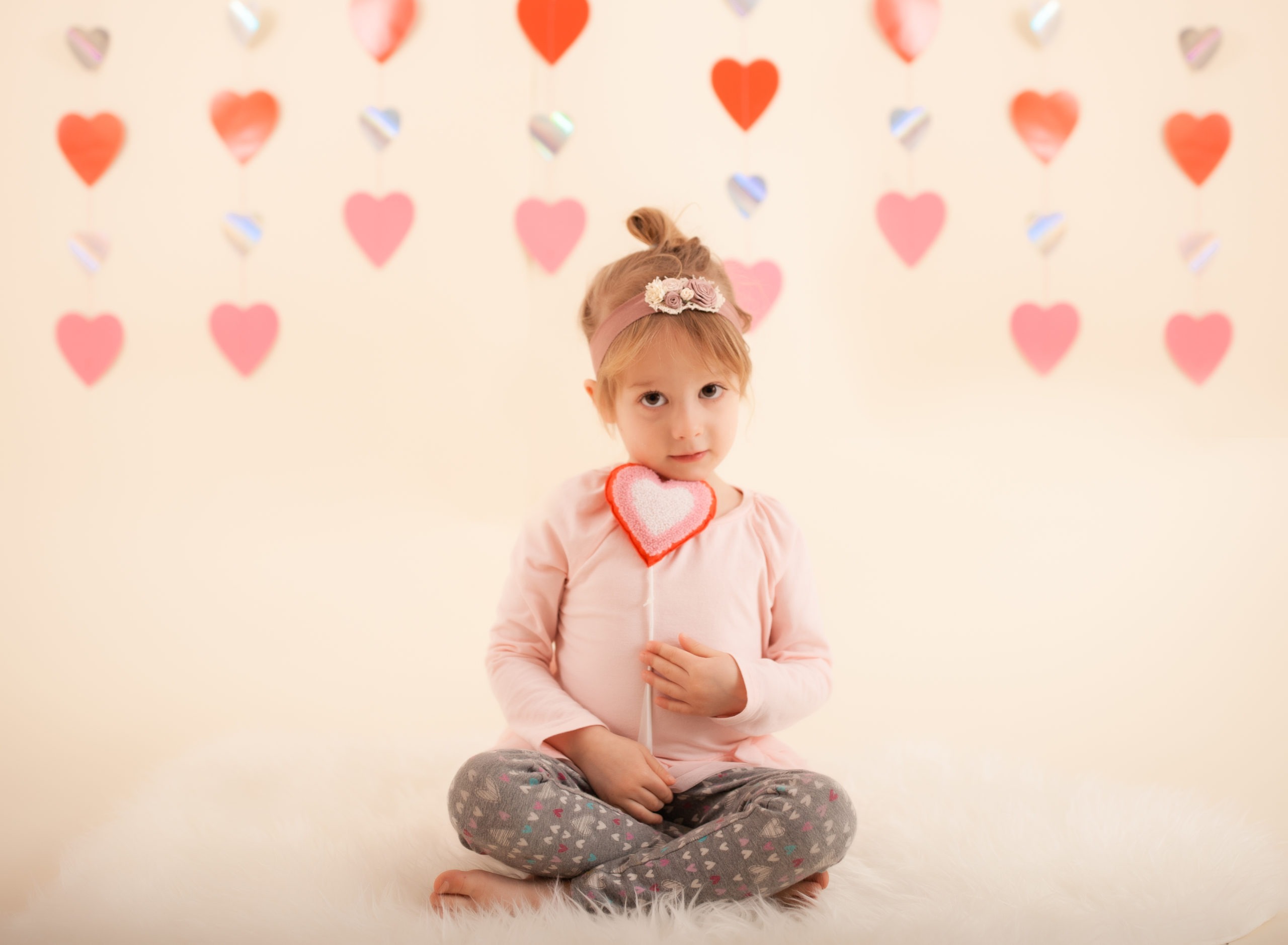Toddler in studio photo shoot in Pasadena, California with valentine day themed props, heart backdrop