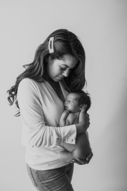 Mother and baby cuddle during newborn photo shoot in studio