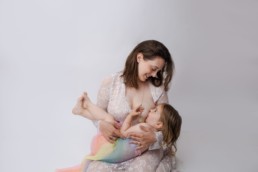 Mother and toddler in studio during photo session breastfeeding
