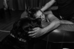 Women touches dog during a contraction of labor while laying in a birth tub