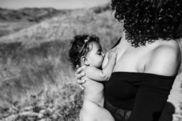Black and white image of mother holding baby upright as she breastfeeds baby
