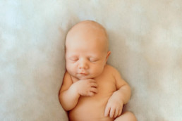 Image of newborn baby laying on fluffy blanket asleep