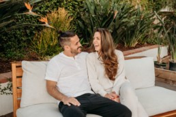 Couple sitting on couch look at each other while laughing