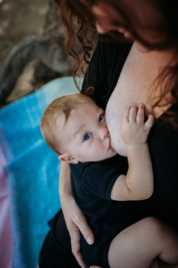 Photo of mother breastfeeding baby, baby looks up at the camera