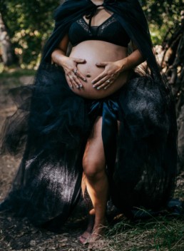 Pregnant mother dressed in black tulle holds her belly