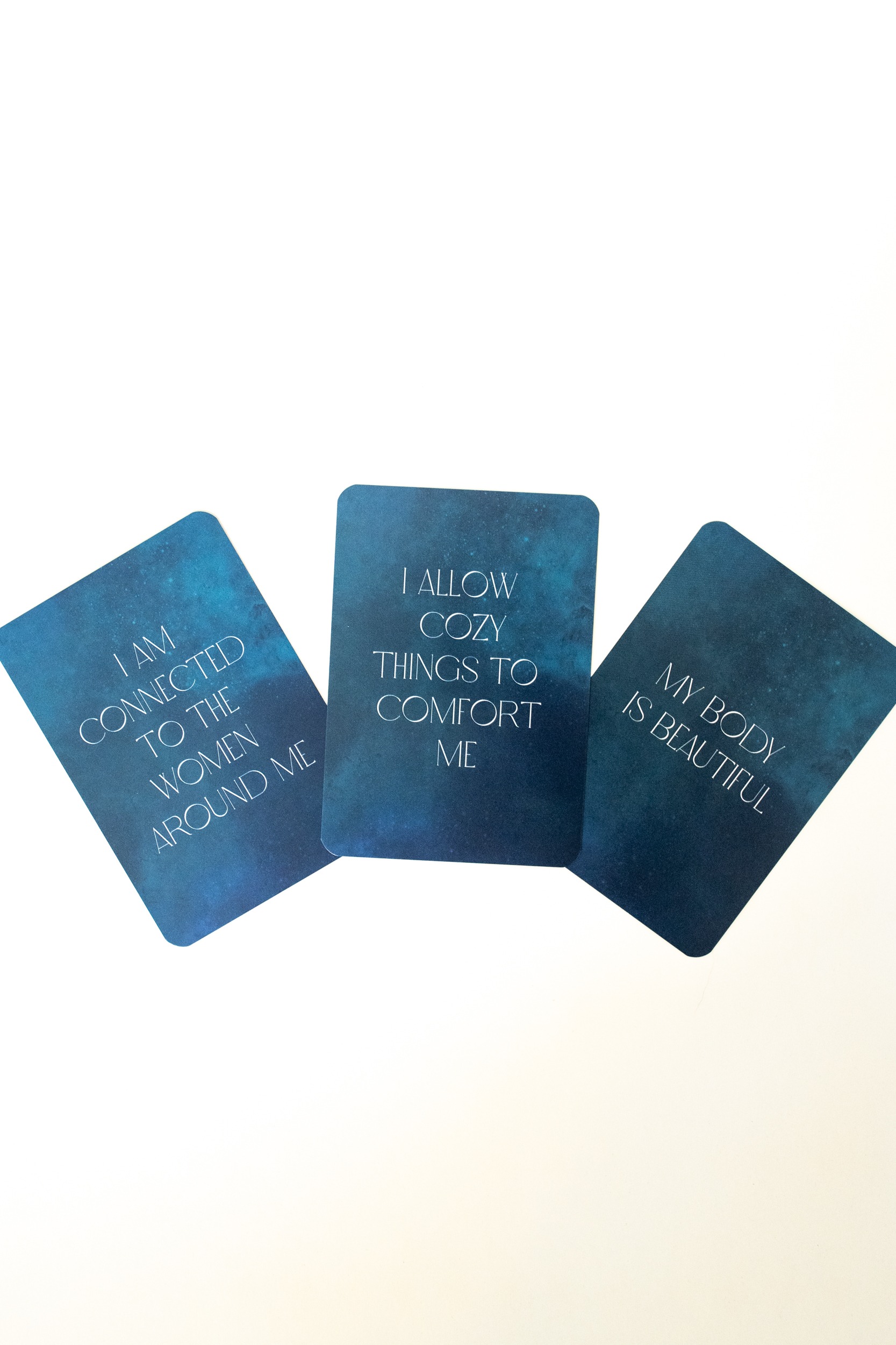 Photo of affirmation card deck entitled Encircled - period affirmation cards. Dark blue deck with golden flower pictured on the front